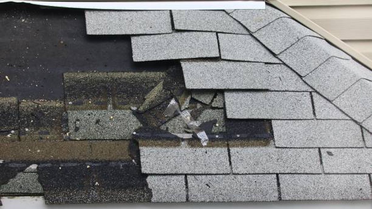 A close view of worn roof shingles during an inspection